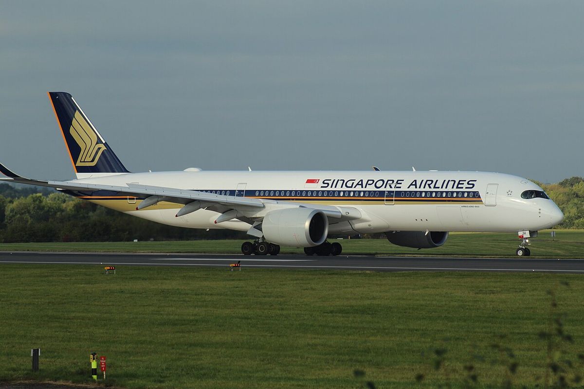 A white Singapore Airlines Airbus A350 with a dark blue and yellow tail on a runway under a gray sky.