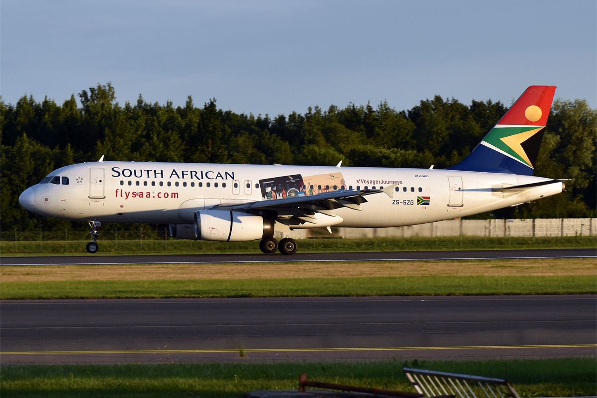 A white South African Airways Airbus A320 with the national flag colors on its tail, on the runway.